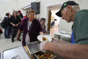 Ed Primas, a volunteer fro the Lutheran Church of the Good Shepherd, dishes out hot food.